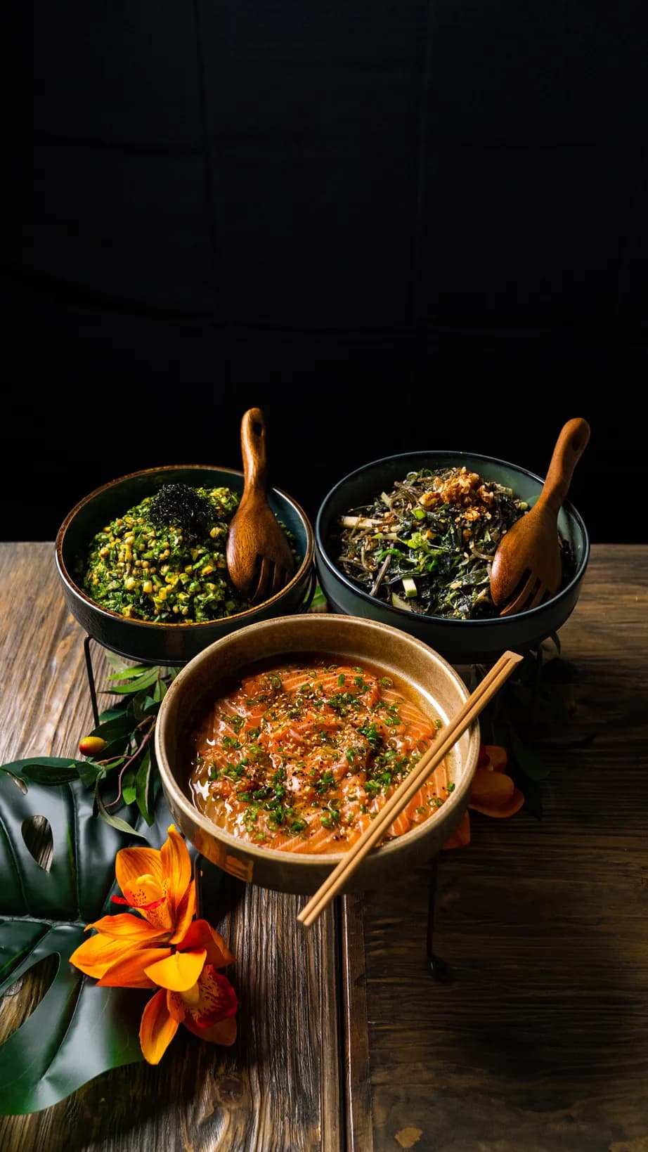 Catering by 3Fils — three handcrafted bowls of Asian cuisine on a rustic dark table