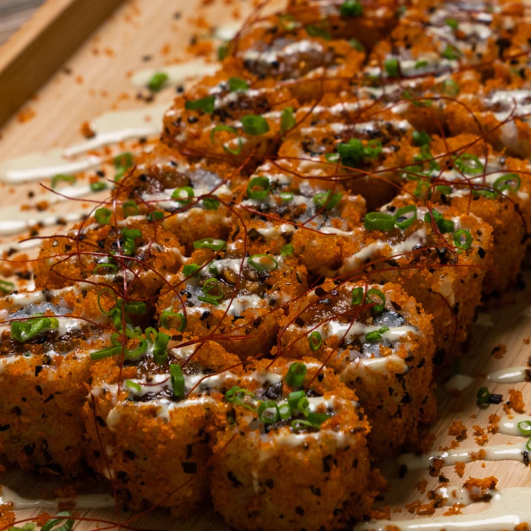 Close-up of signature 3Fils crispy sushi rolls with saffron threads and spring onion garnish