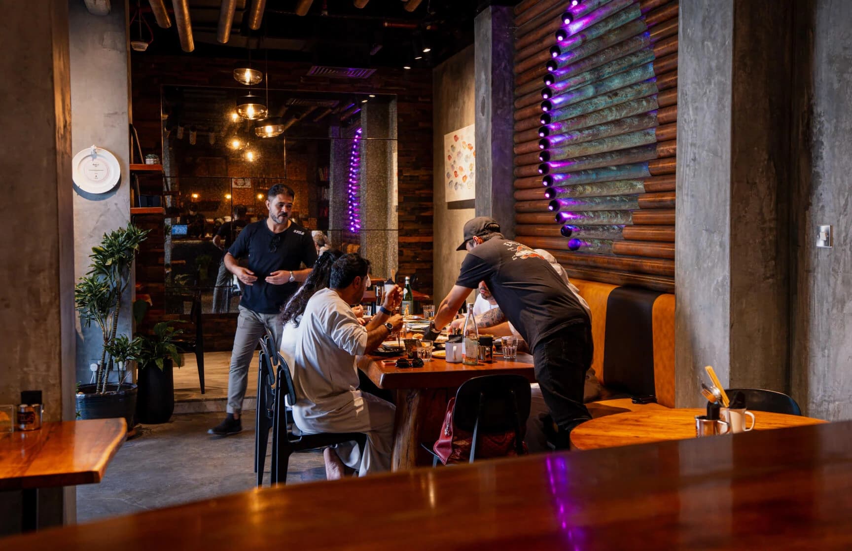 Inside 3Fils — warm wooden tables, ambient lighting, and guests enjoying the experience